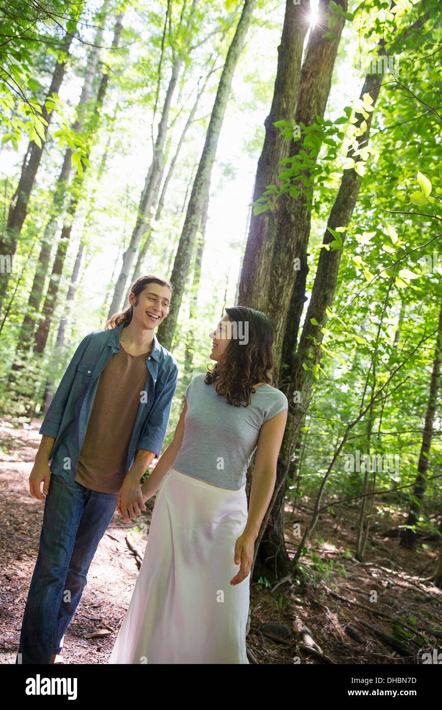 Two people, a young woman and man, walking side by side in the woods ...