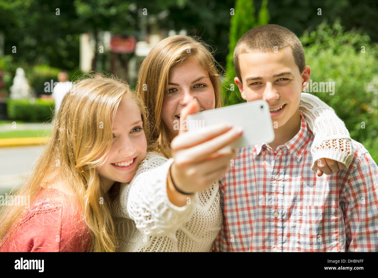 Three young people, two girls and a boy, posing and taking selfy photographs. Stock Photo