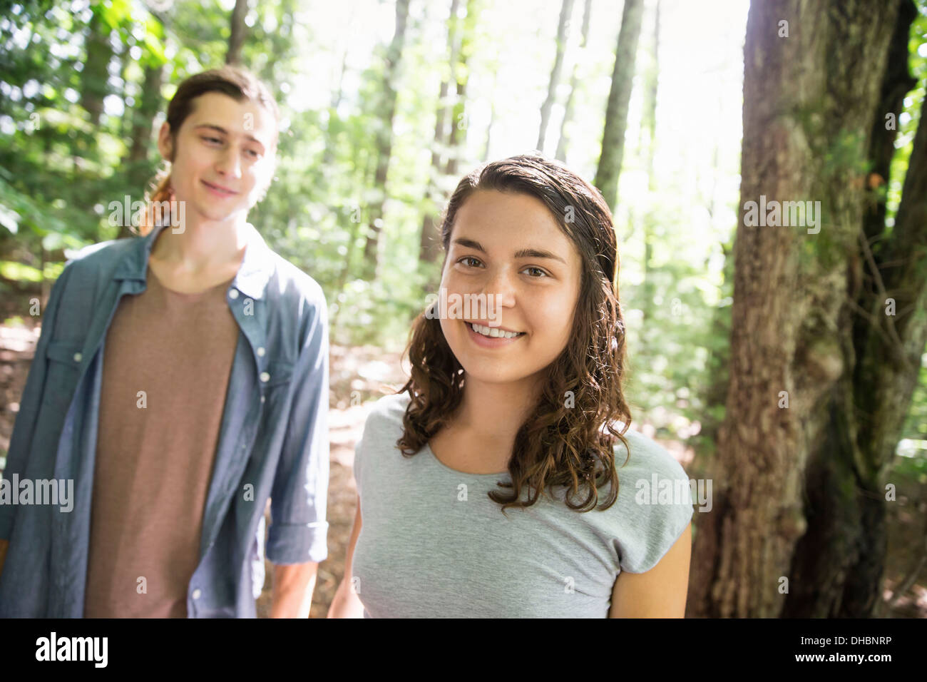 Two people, a young woman and man, walking side by side in the woods. Stock Photo