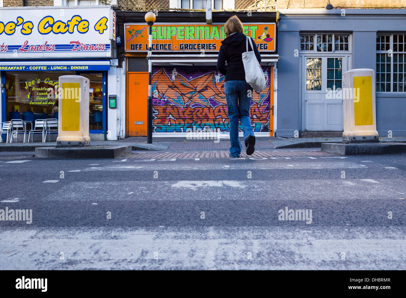 A women crosses a Pelican Crossing on the Caledonian Road in Islington North London. Stock Photo