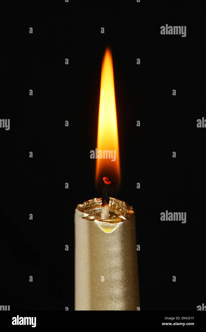 Burning gold candle against a black background Stock Photo Alamy