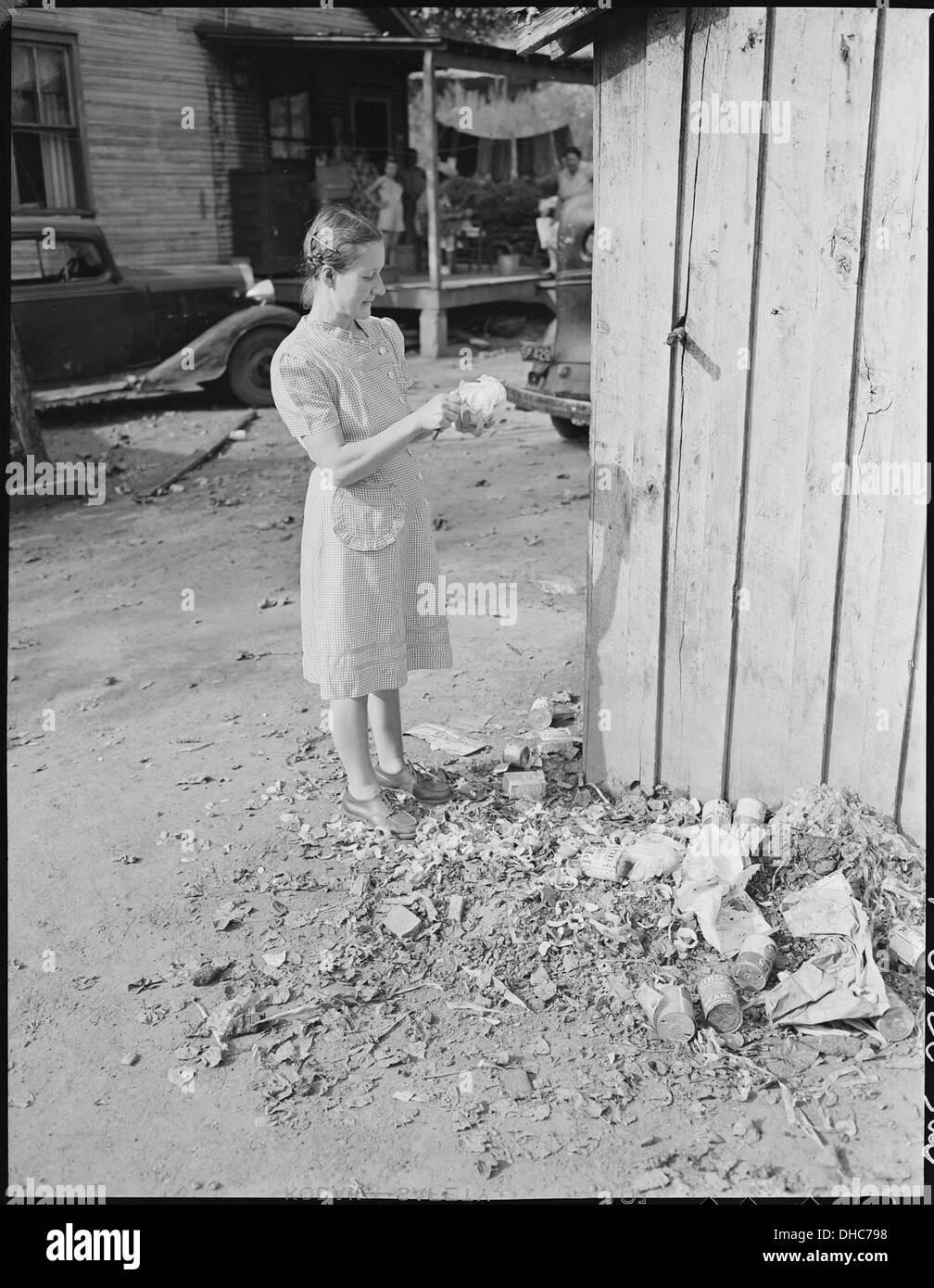 Mrs. Virgil Price, wife of miner, peels a head of lettuce in garbage