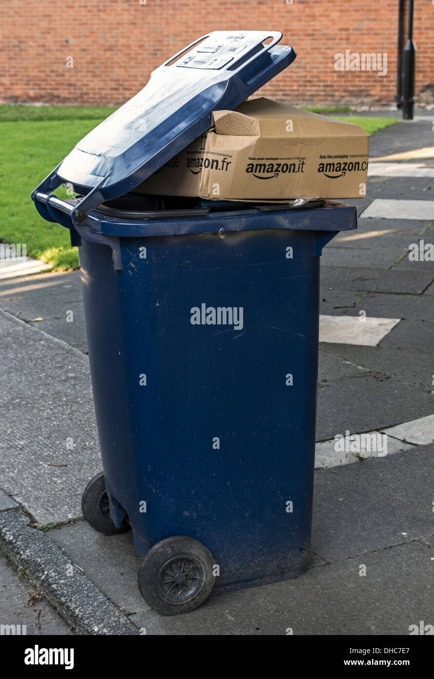 A wheelie bin overflows with waste including a brown packing box bearing the Amazon logo of the internet shopping firm. Stock Photo