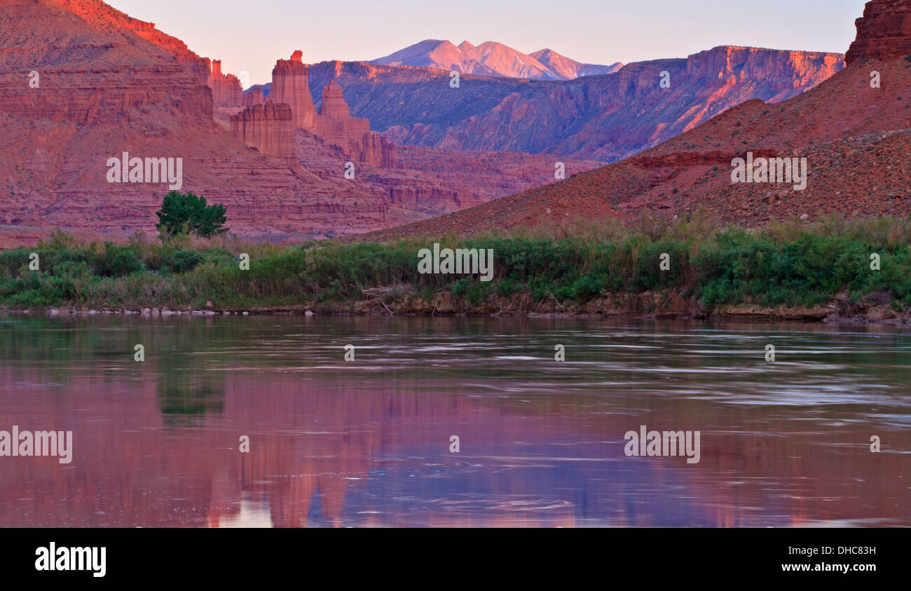 Fisher Towers partially lit by the last of the setting sun and purple mountains reflected in the Colorado River near Moab,Utah Stock Photo