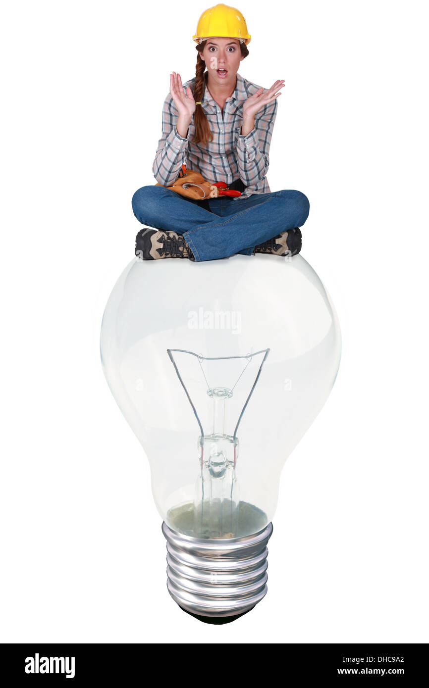 Woman with expression of surprise sat on a big light bulb Stock Photo