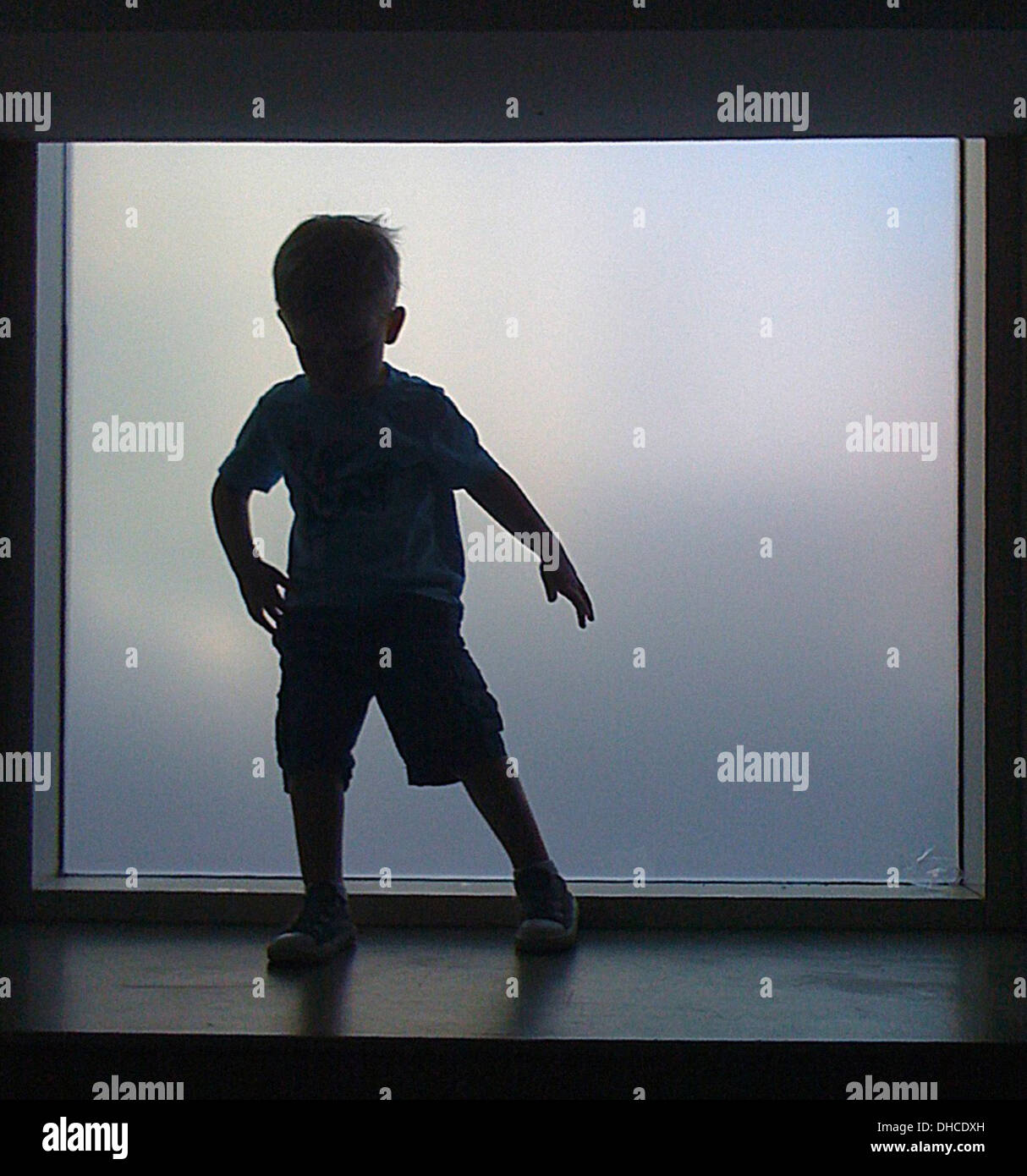 Silhouette of Young Boy Standing on Ledge in Front of Opaque Window ...