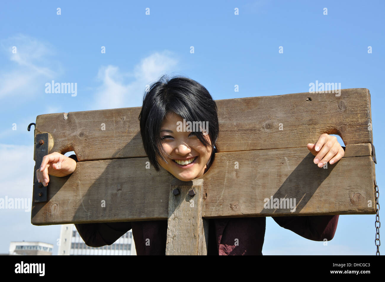 young Japanese woman in wooden stocks in grounds of Nottingham Castle, Nottingham, England, UK Stock Photo