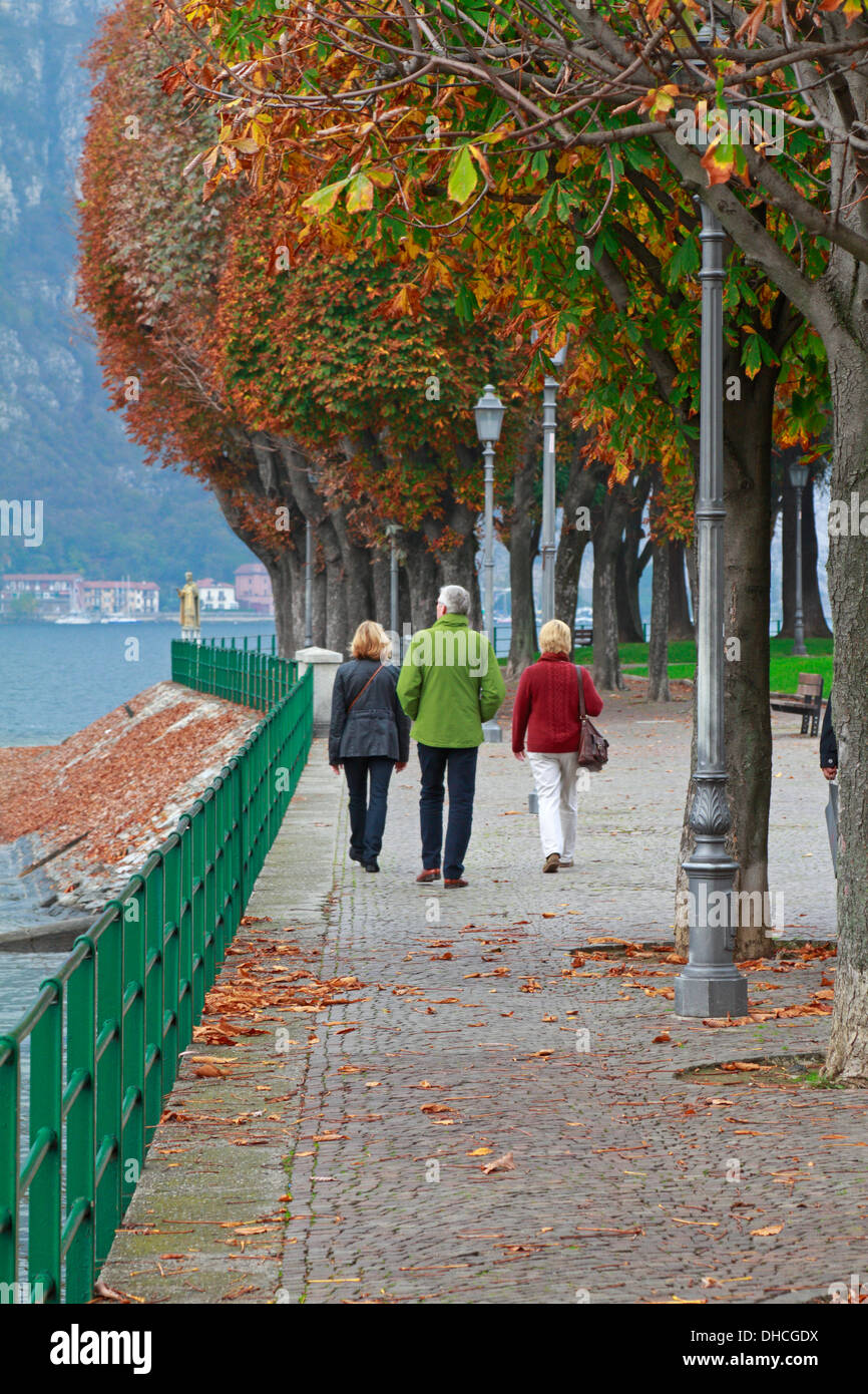 Three people walking along the tree lines promenade by Lake Como in Lecco,  Italy in Autumn Stock Photo - Alamy, image size:866x1390