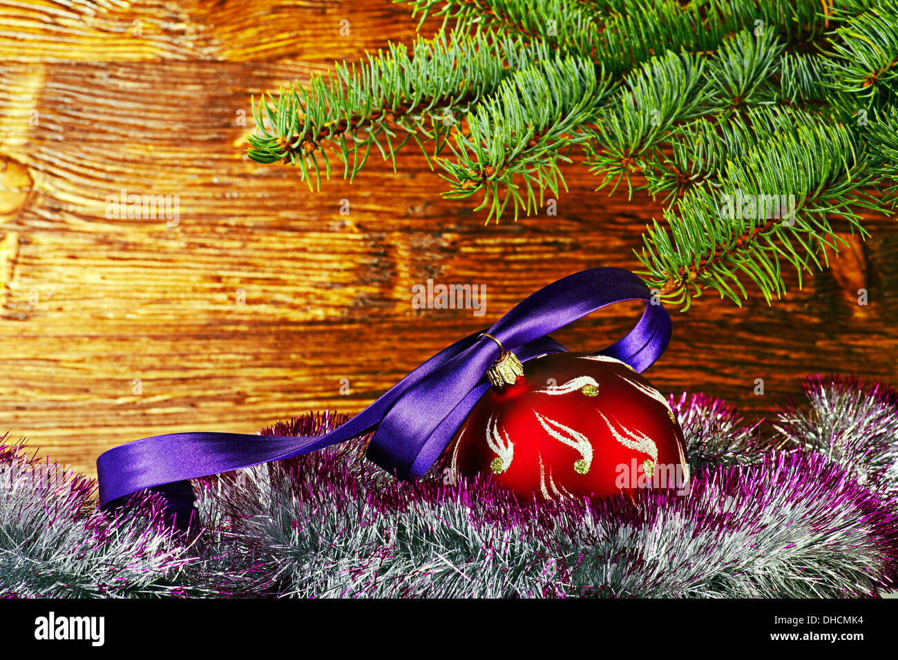 Christmas decoration. Red ball with violet ribbon, fir-tree and tinsel. Selective focus Stock Photo