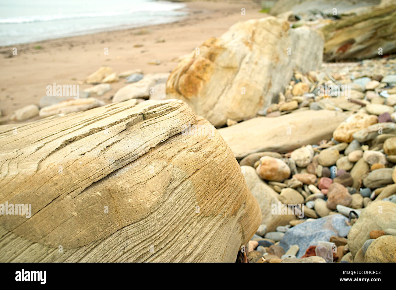 Textured rocks and pebbles on beach with sea in background Stock Photo ...