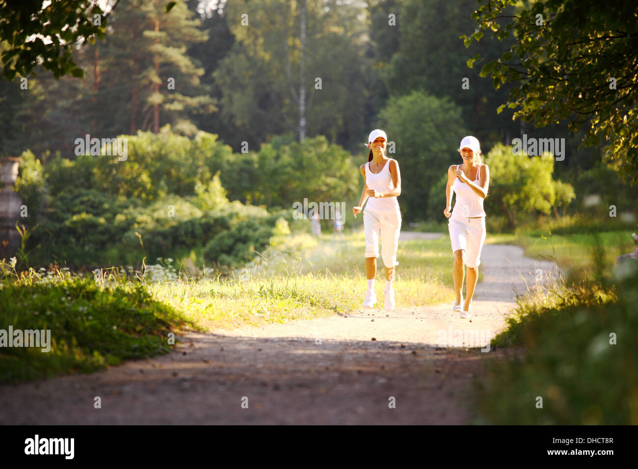 women run by sunny park alley Stock Photo Alamy