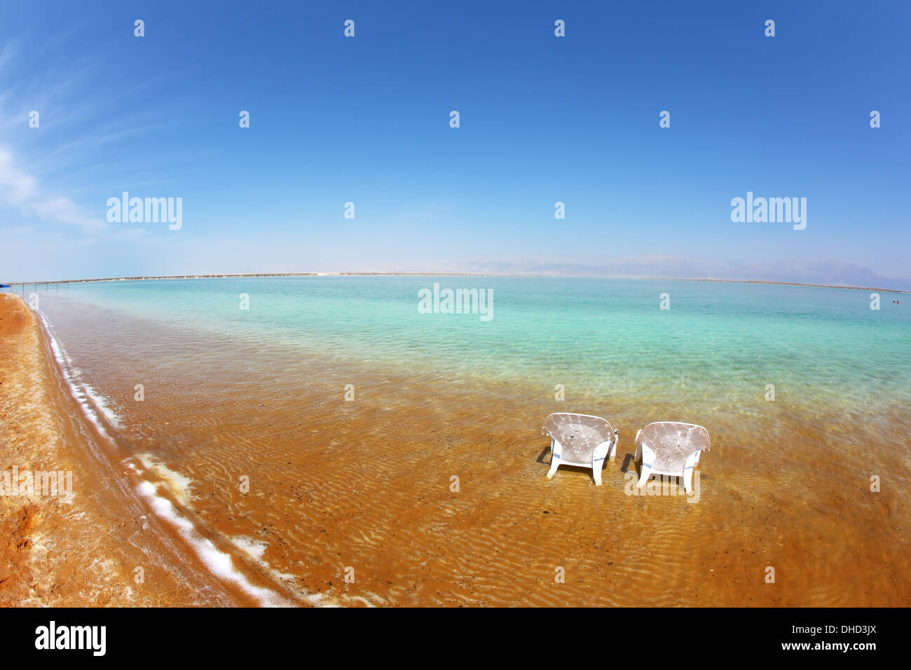 Two white beach chairs stood in the water Stock Photo