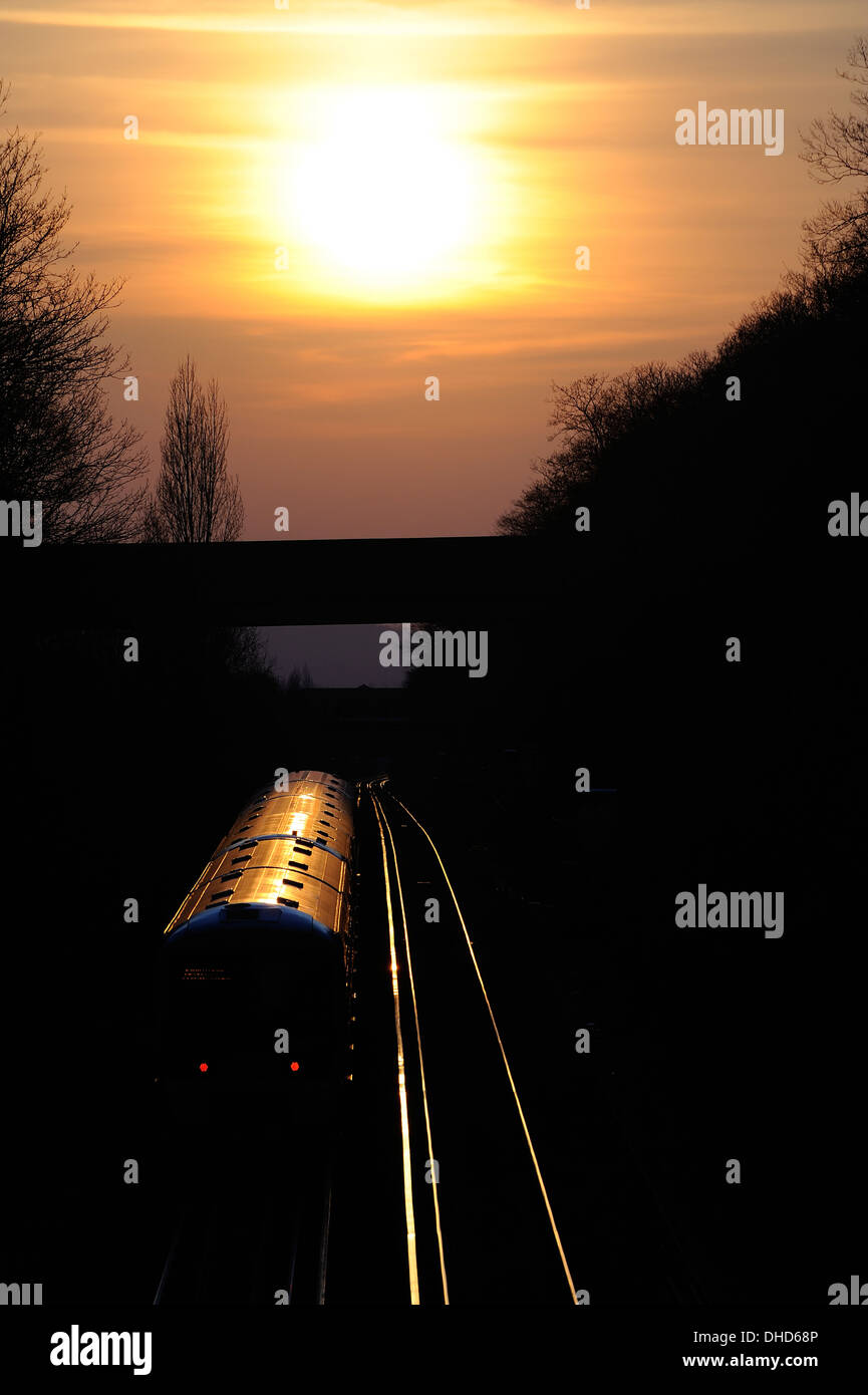 Silhouette of a train driving towards a the setting sun Falconwood London Stock Photo