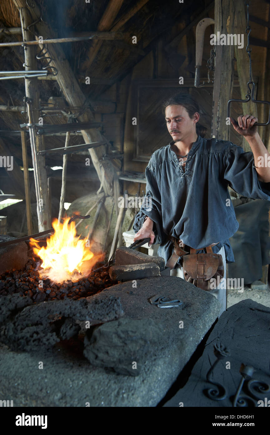 A blacksmith working at a forge in the history theme park of Puy du Fou in France Stock Photo