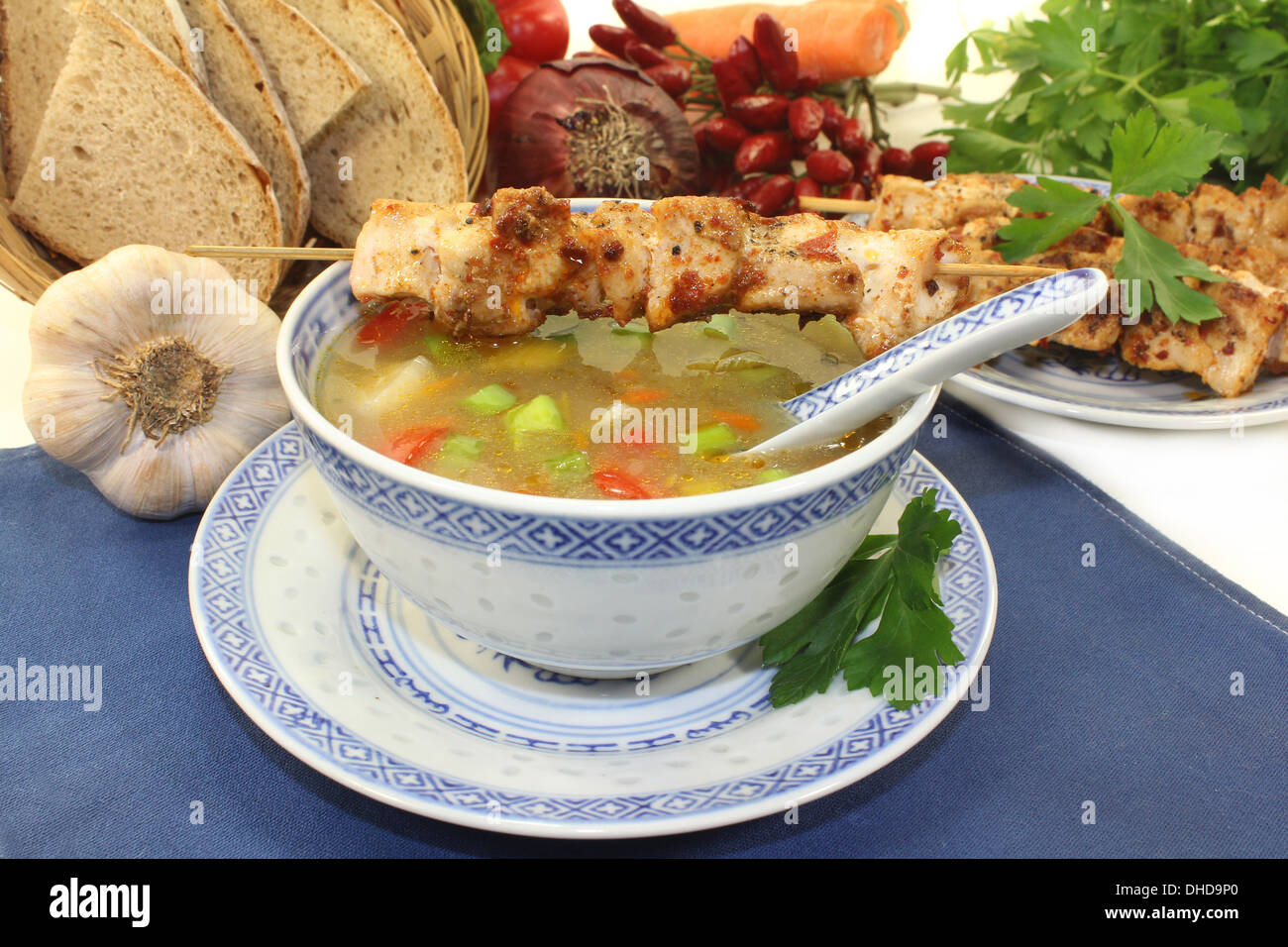 a bowl of chicken consomme and a chicken skewer Stock Photo