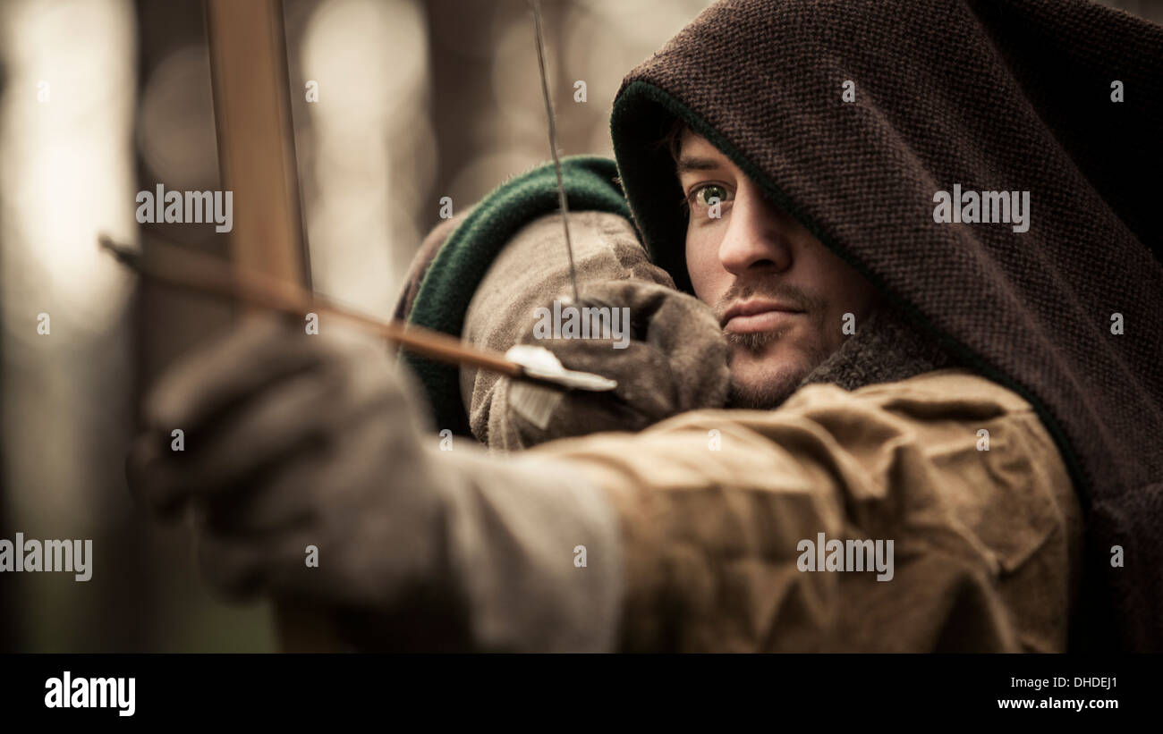 A man dressed in middle ages costume draws back his longbow Stock Photo