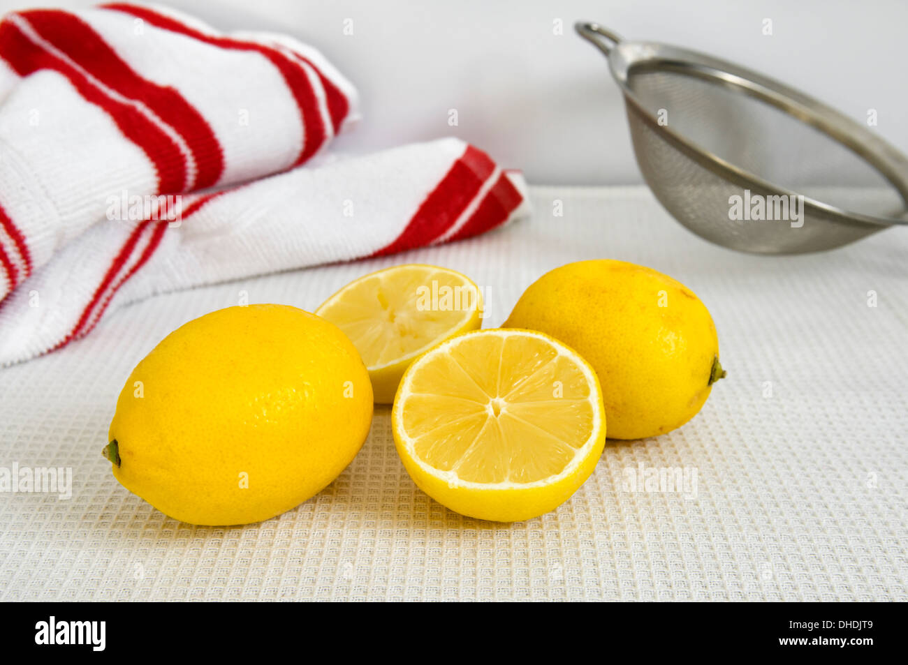 Fresh lemons on work top with tea cloth and sieve in background Stock Photo