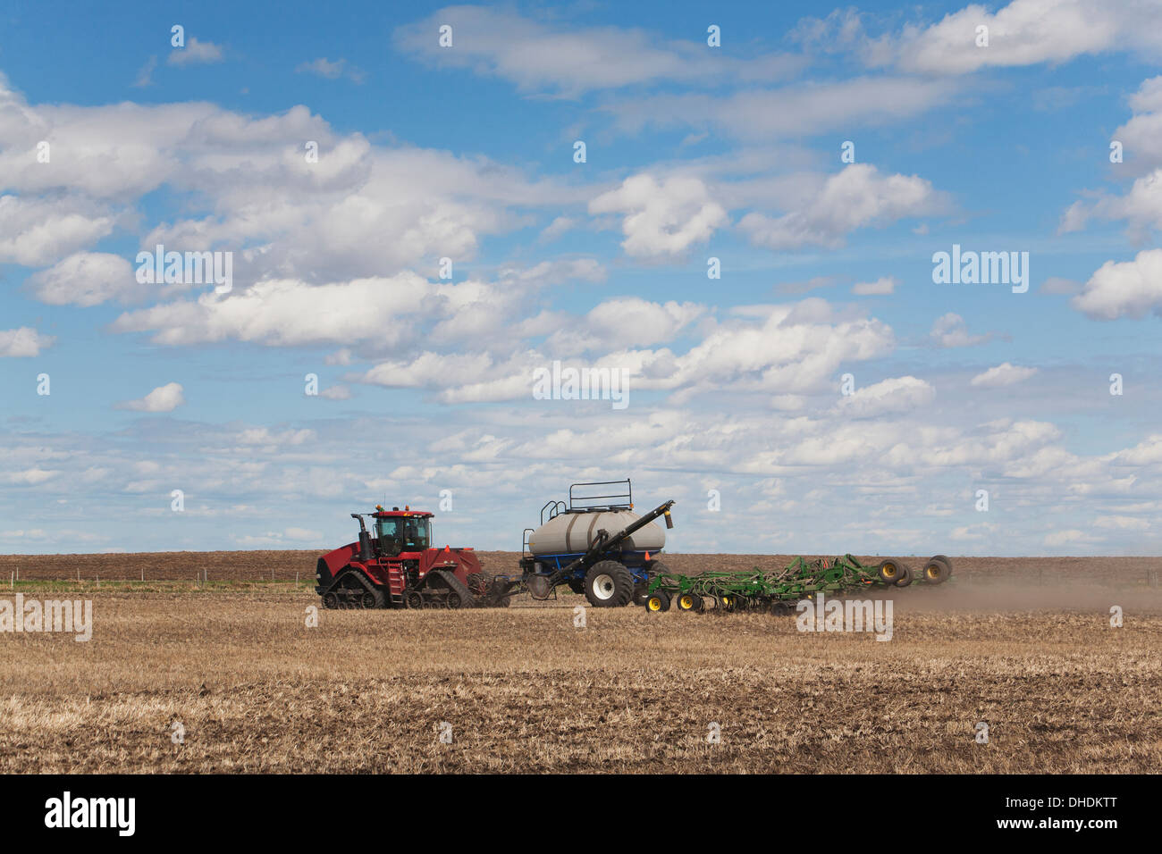 An Air Seeder In A Field With A Tractor And Blue Sky With Cloud; Acme