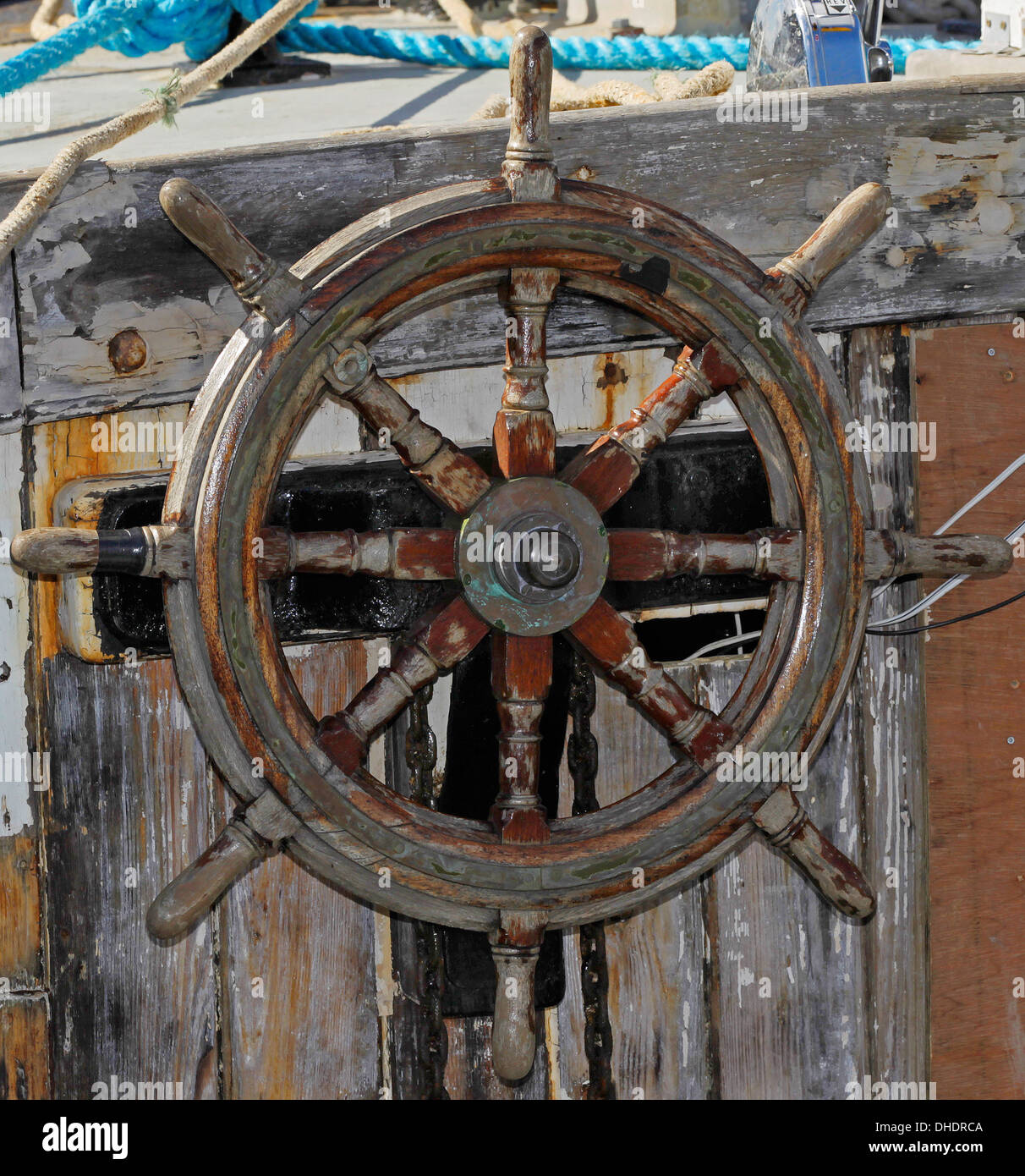 The weather beaten wooden steering wheel of an old boat Stock Photo