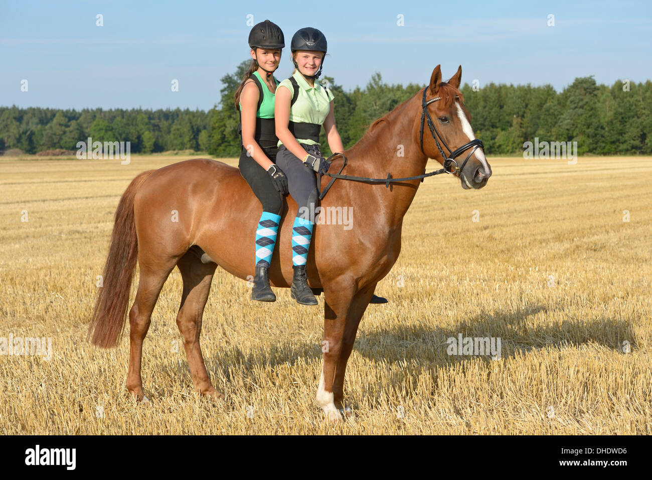 Two girls (wearing helmet and back protector) riding together on back