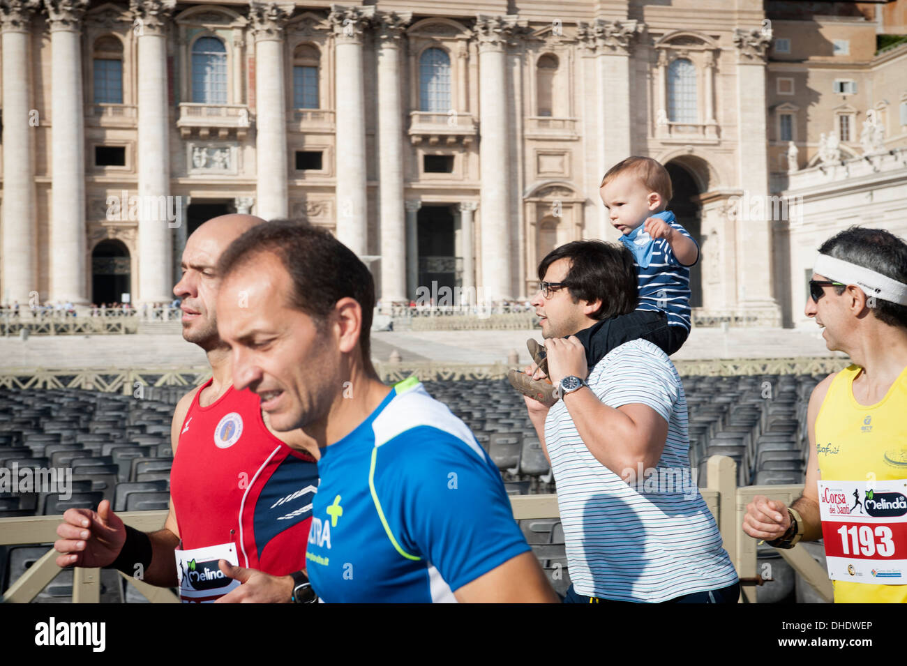Father runs with his son on his shoulders before race in Vatican city Stock Photo