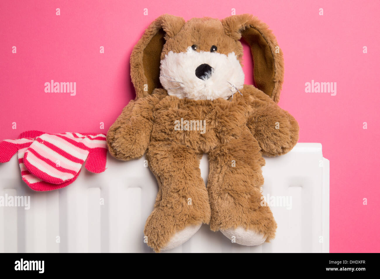 A child's pink bedroom with a teddy bear and a pair of mittens placed on top of a radiator heater. Stock Photo