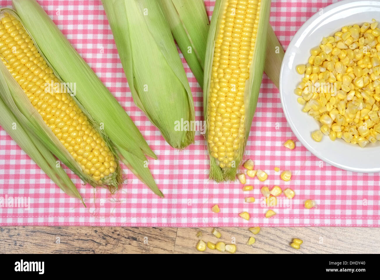 A bowl of sweetcorn and corn on the cob placed on a pink checker pattern tablecloth Stock Photo