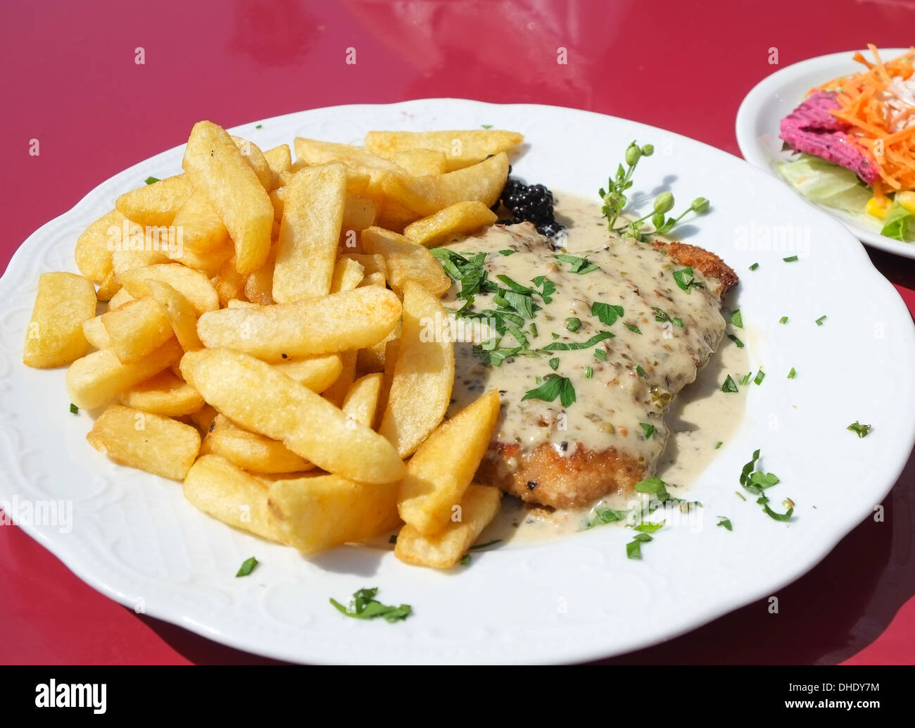 A schnitzel with a pepper sauce, served with fries and a side salad Stock Photo