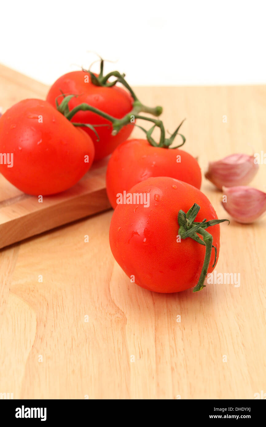 Close-up of fresh tomato's and garlic cloves on a cutting board - studio shot Stock Photo