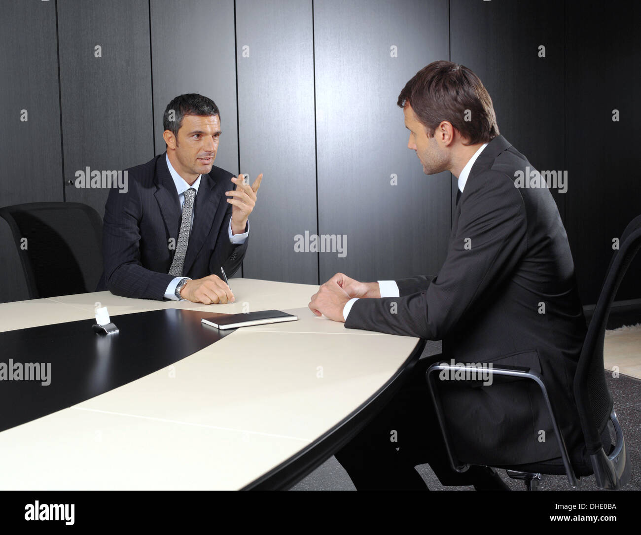 Two businessmen discussing tasks sitting at office table Stock Photo