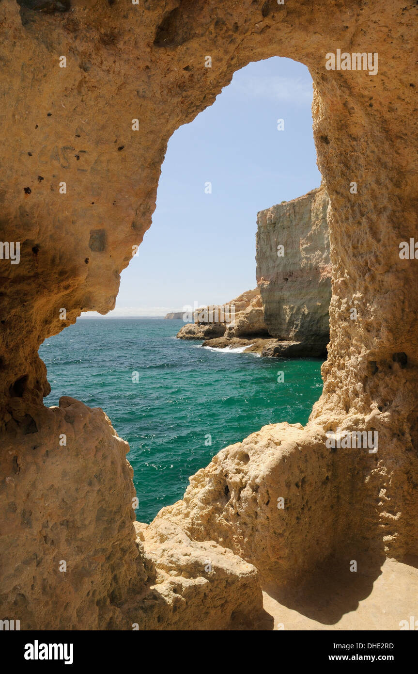 View along the coast from cave within highly eroded sandstone cliffs at Algar Seco Parque, near Carvoeiro, Algarve, Portugal. Stock Photo