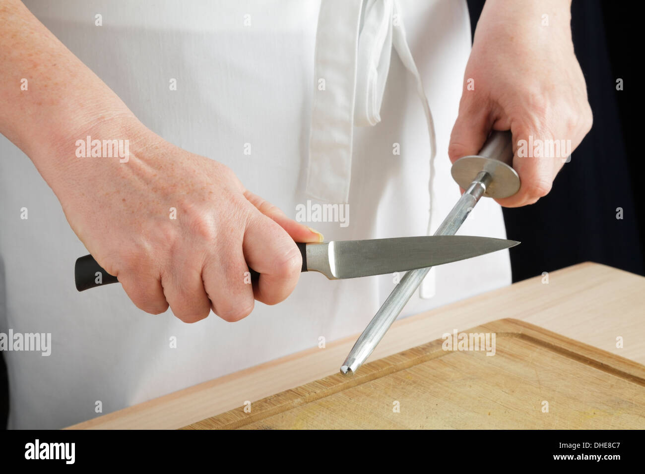 Closeup Of Male Chef Hands Sharpen A Big Chefs Knife Stock Photo