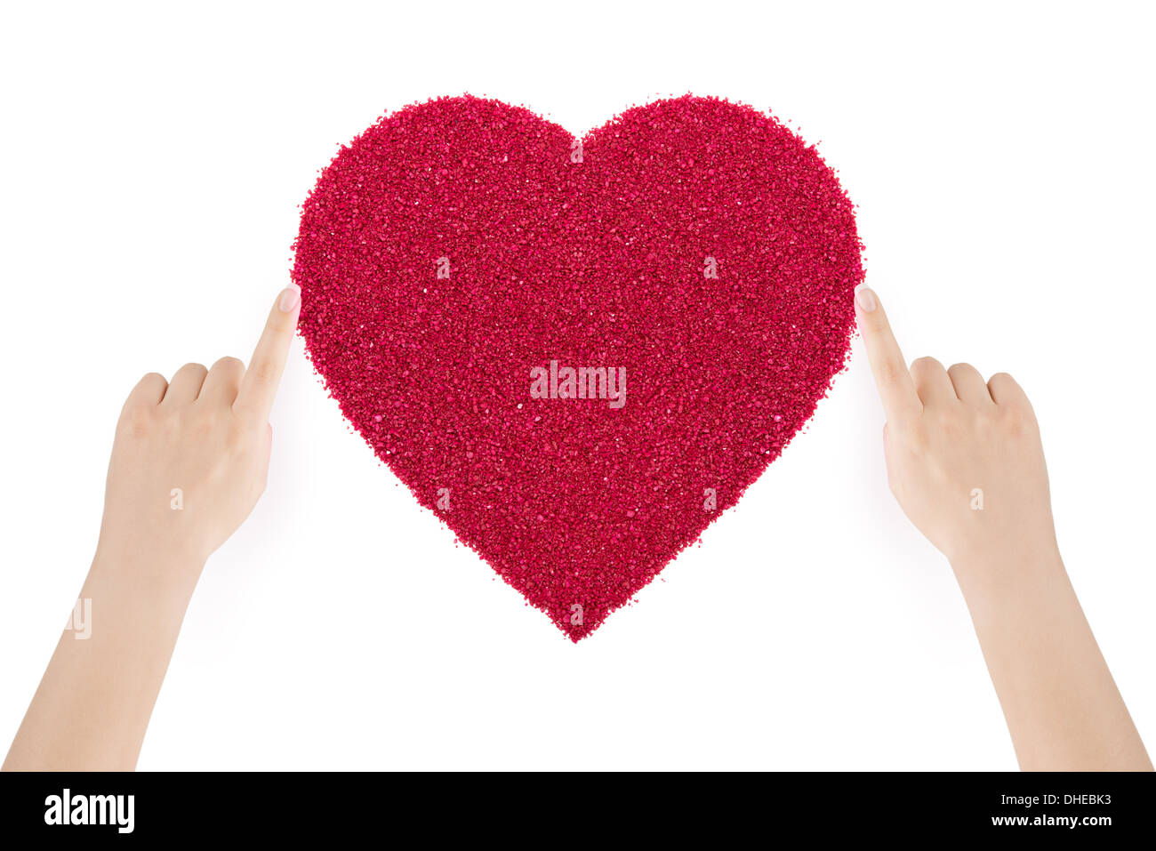 Woman's hands making the heart of red sand by index fingers on white background. Stock Photo