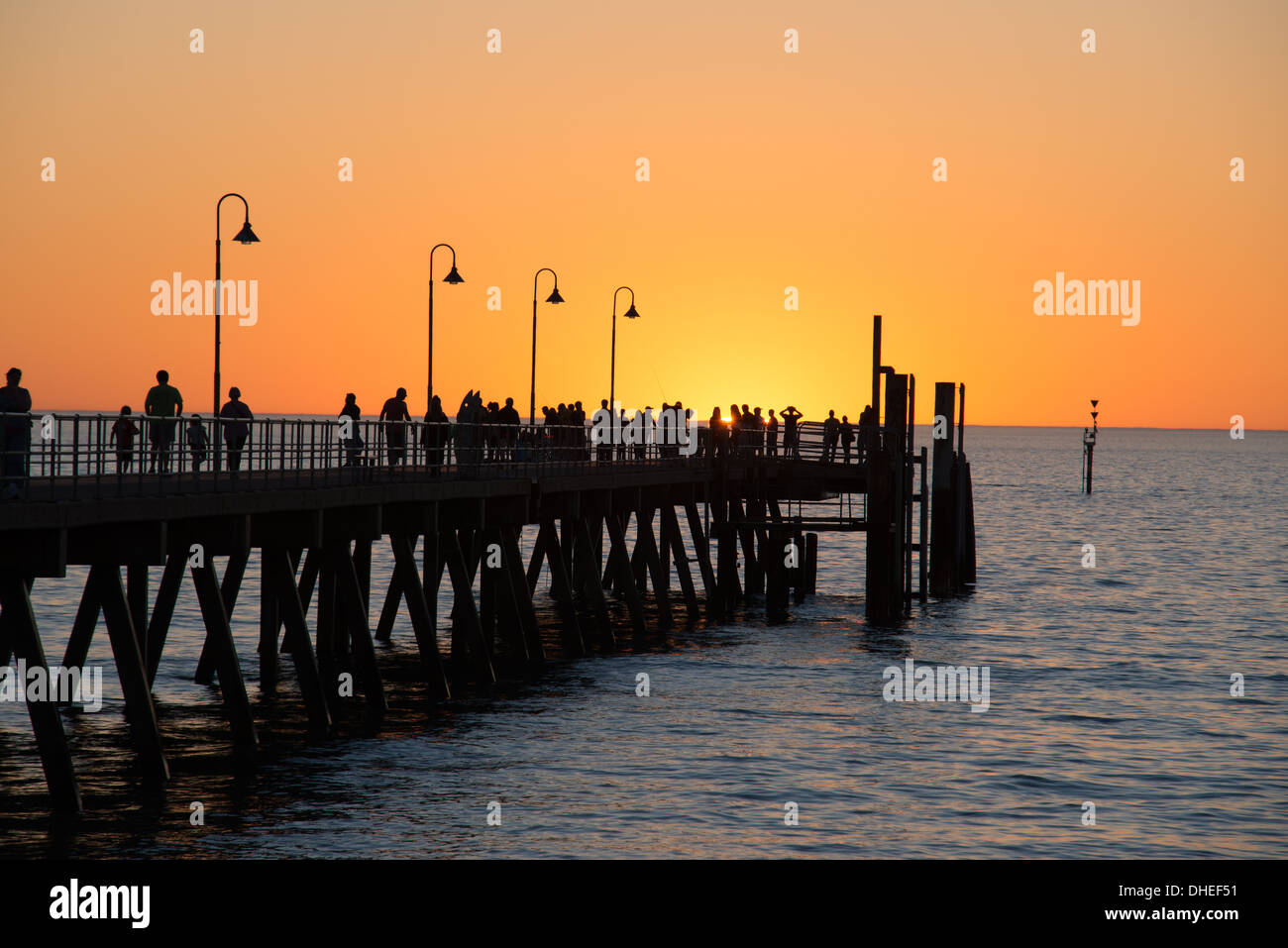People enjoying a sunset walk along the pier at Glenelg jetty Australia in Summer Stock Photo