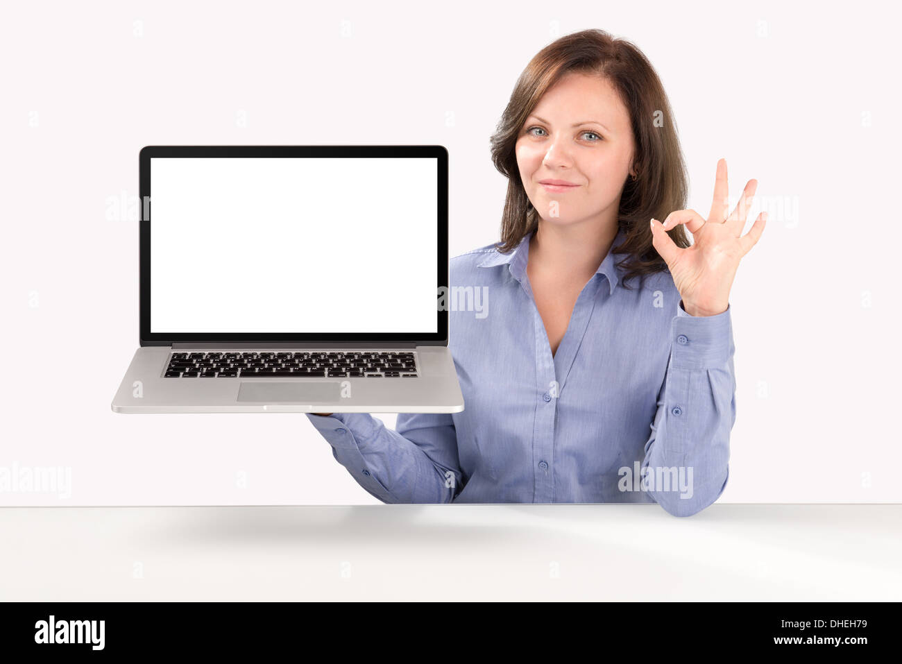 Business woman is holding a laptop in one hand and by other hand showing ok gesture, business concept Stock Photo