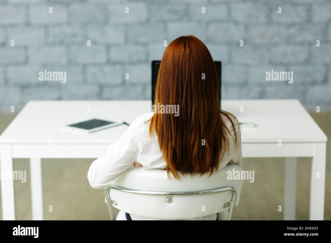 Picture from behind of a businesswoman sitting at her desk Stock Photo