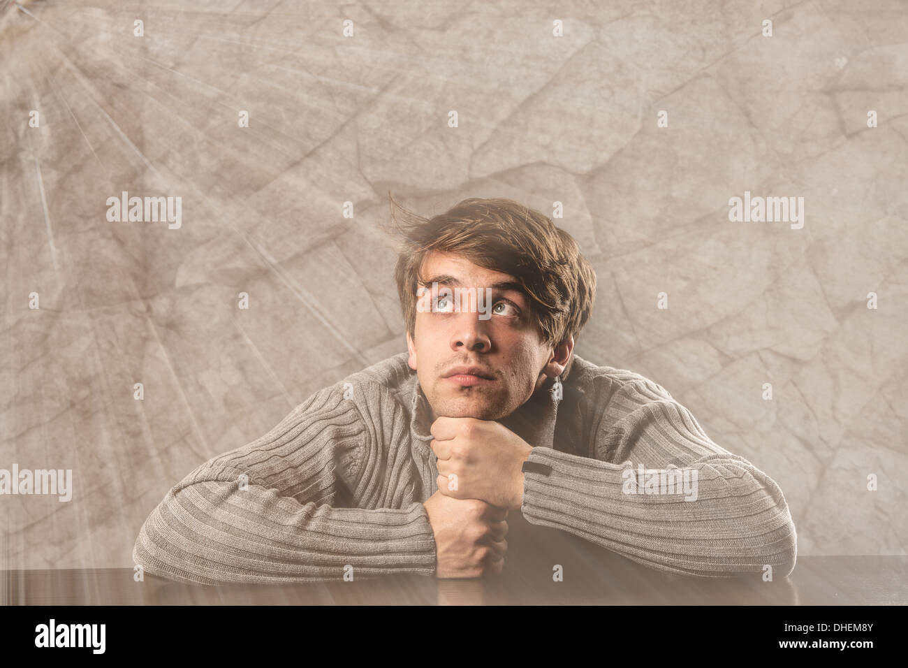 Pensive young man in gray pullover over gray background Stock Photo