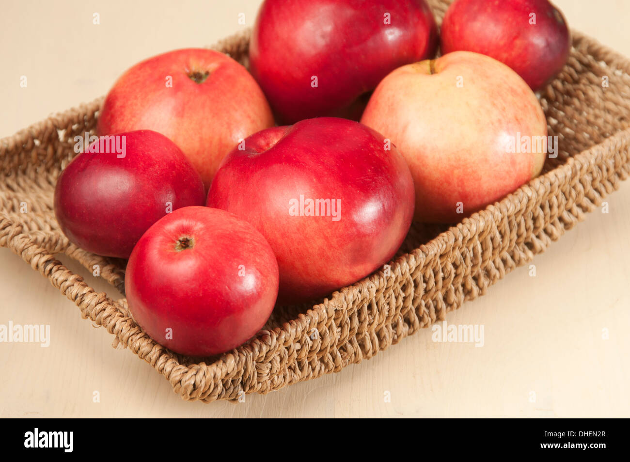 Beautiful red apples in a twiggen bowl on a table Stock Photo