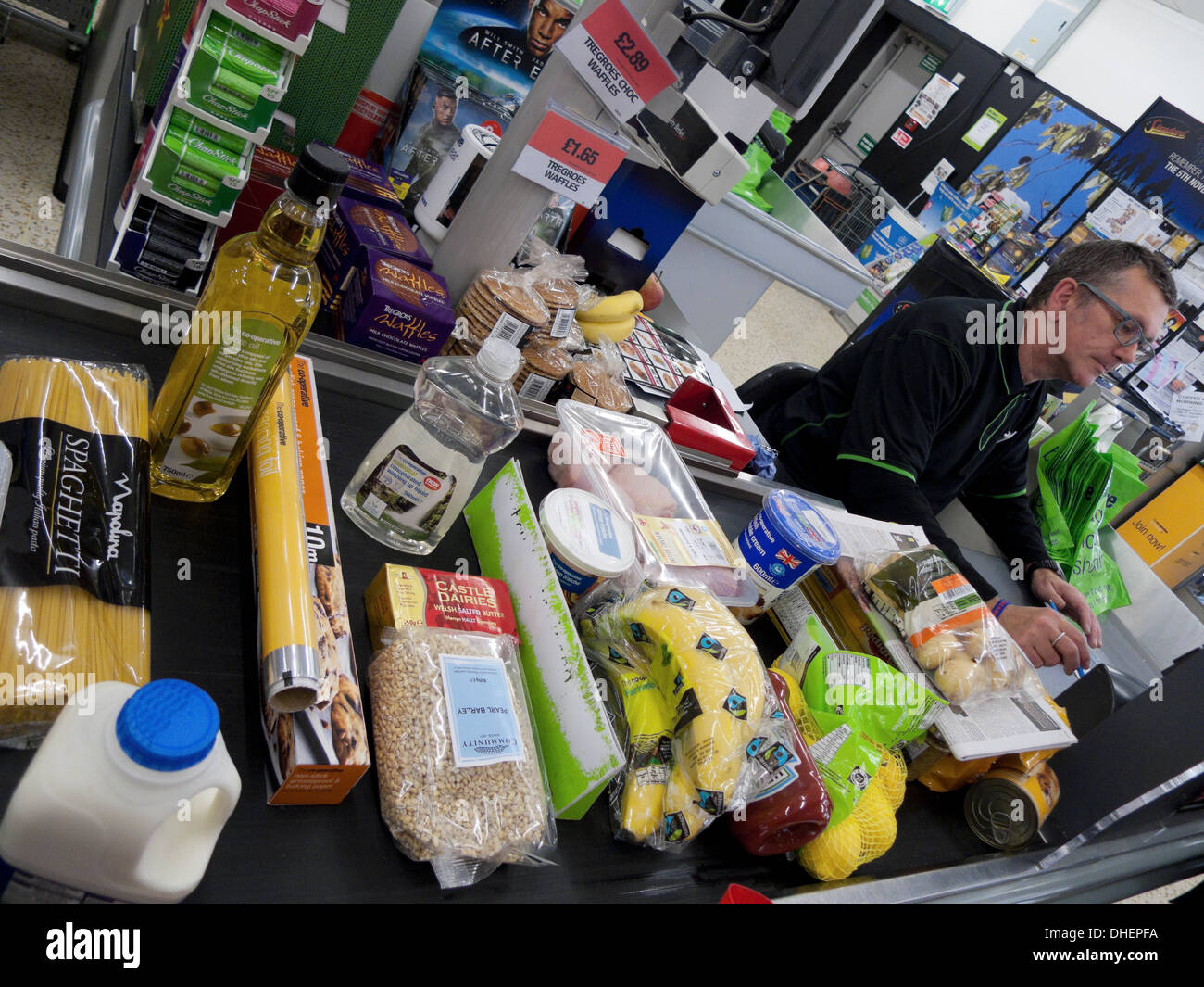 A male employee working at the checkout counter filled with groceries food in Co-Op supermarket Wales UK KATHY DEWITT Stock Photo