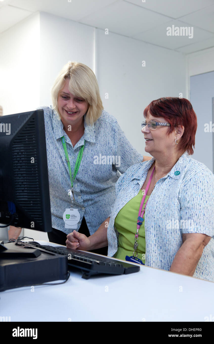 Hospital receptionists check appointments in an outpatient depatment UK Stock Photo