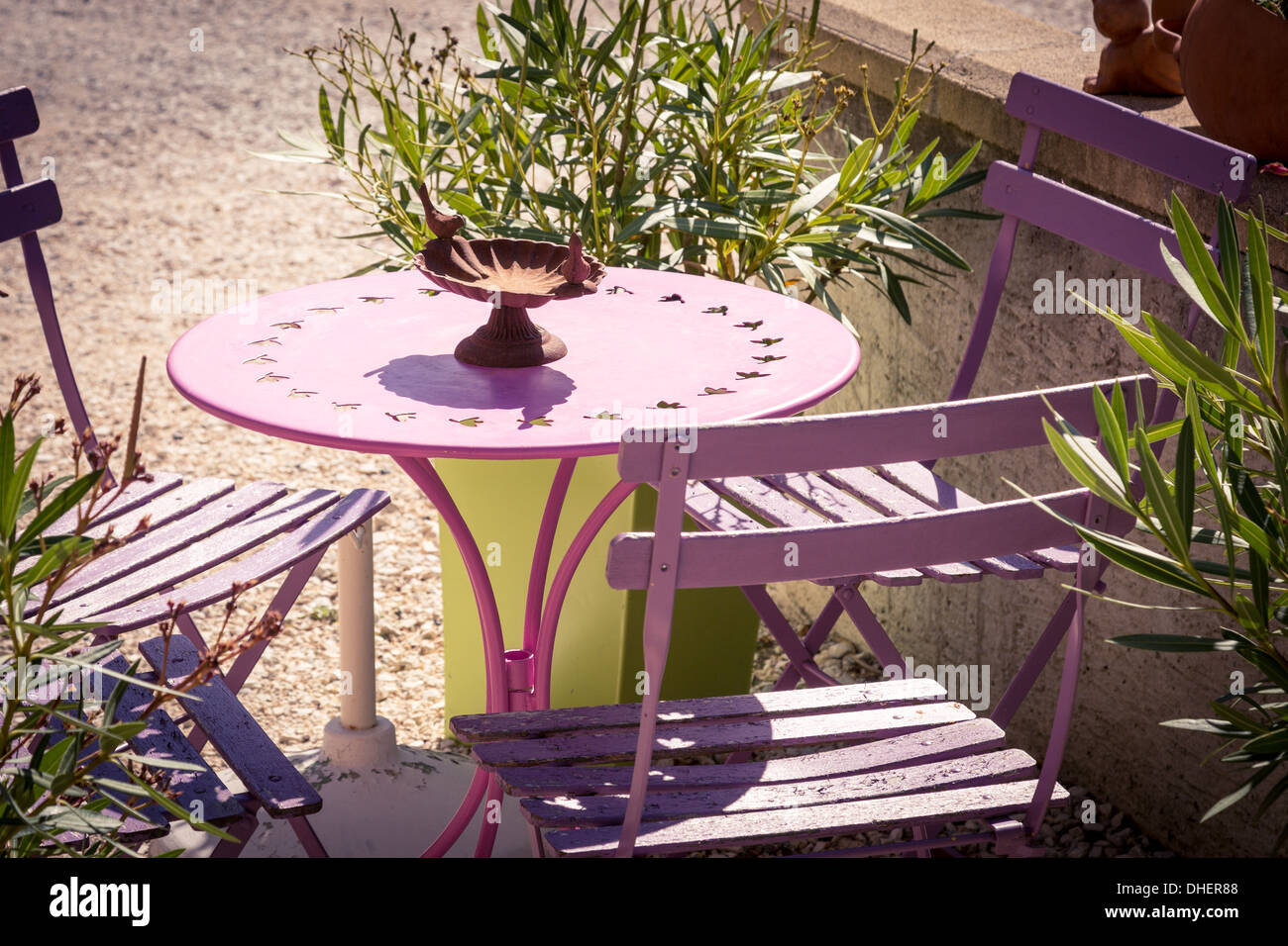 traditional cafe style table and chairs in a sunny French garden. Stock Photo