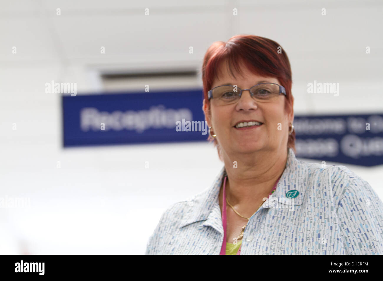 A welcoming hospital receptionist smiles to camera UK Stock Photo