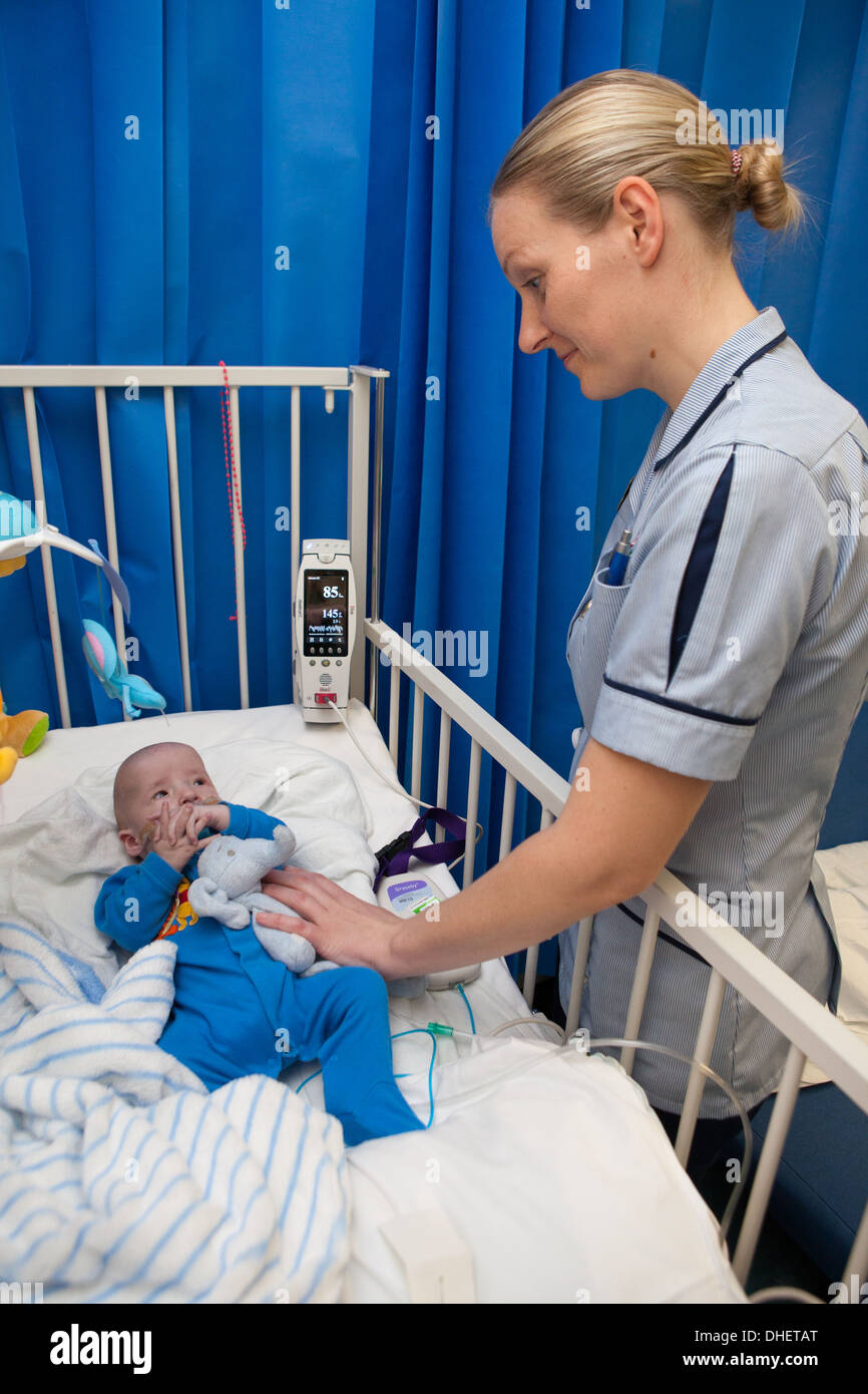 A pediatric nurse looks after a baby in her care UK Stock Photo