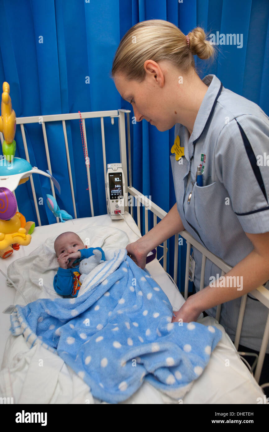 A pediatric nurse looks after a baby in her care UK Stock Photo