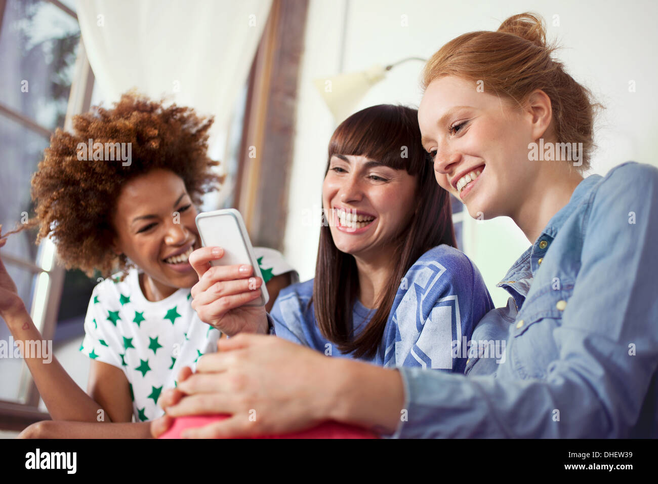 Three female friends using smartphone Stock Photo