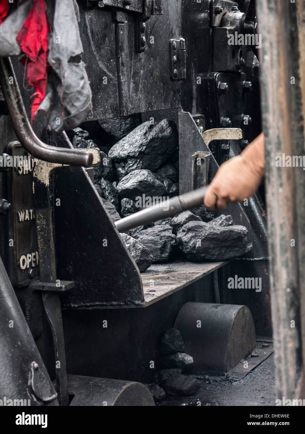 Person shoveling coal on a steam train  Norfolk England Stock Photo