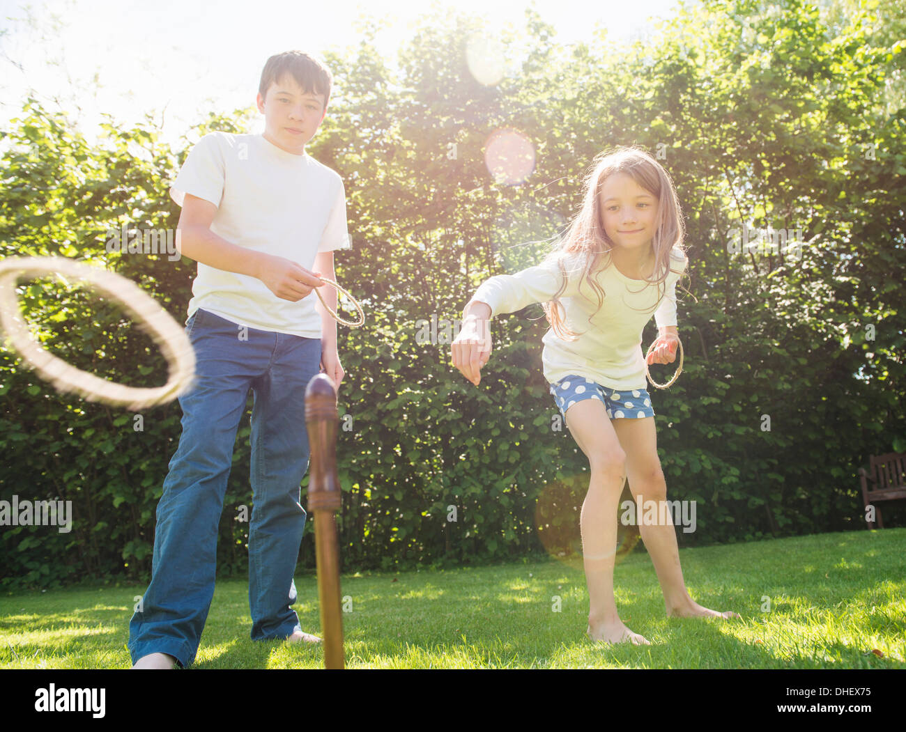 Brother and sister playing hoopla in garden Stock Photo