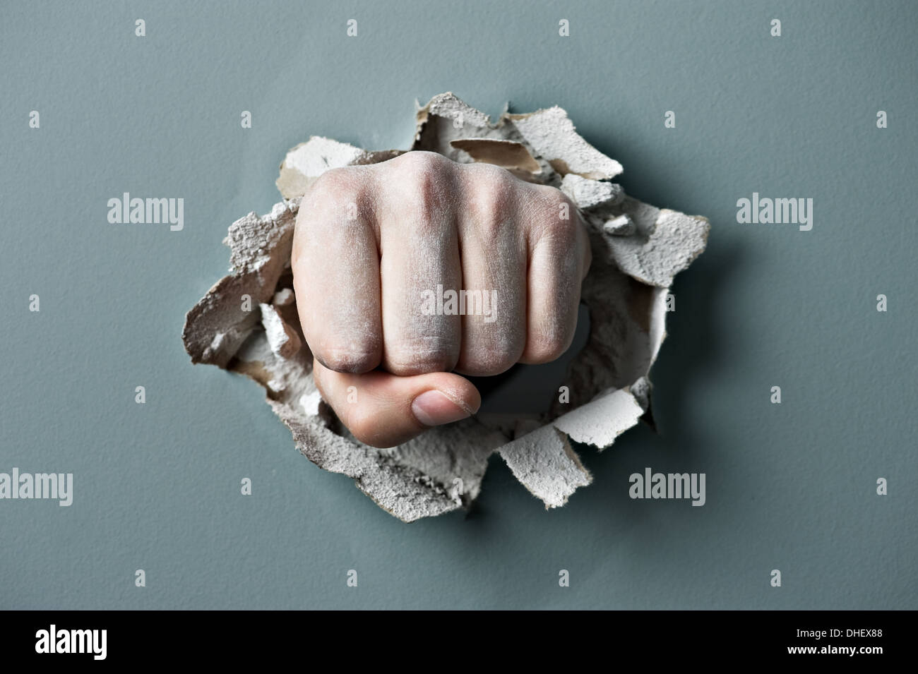 a wall is broken through by a fist Stock Photo