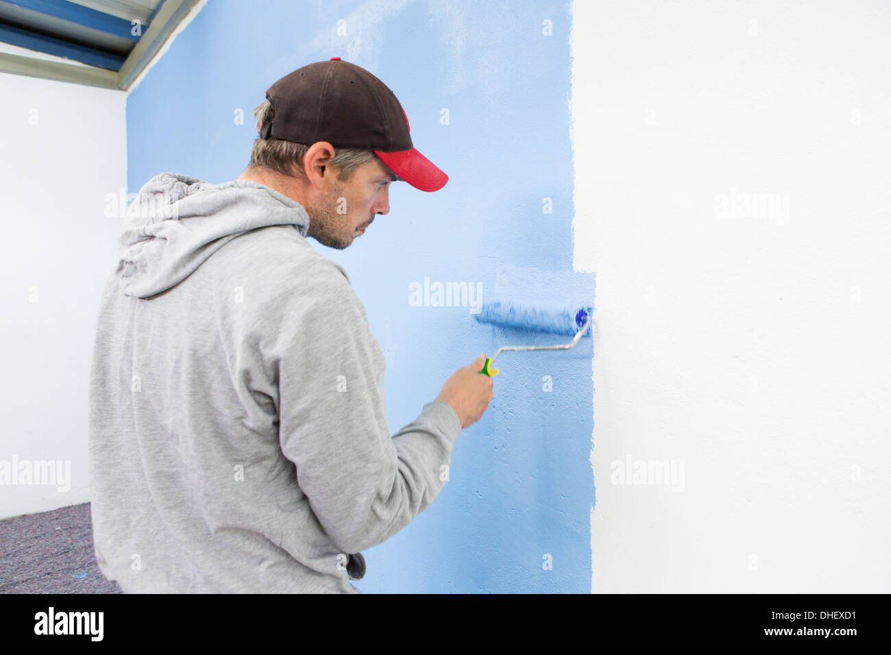 Rear view of man painting wall blue Stock Photo