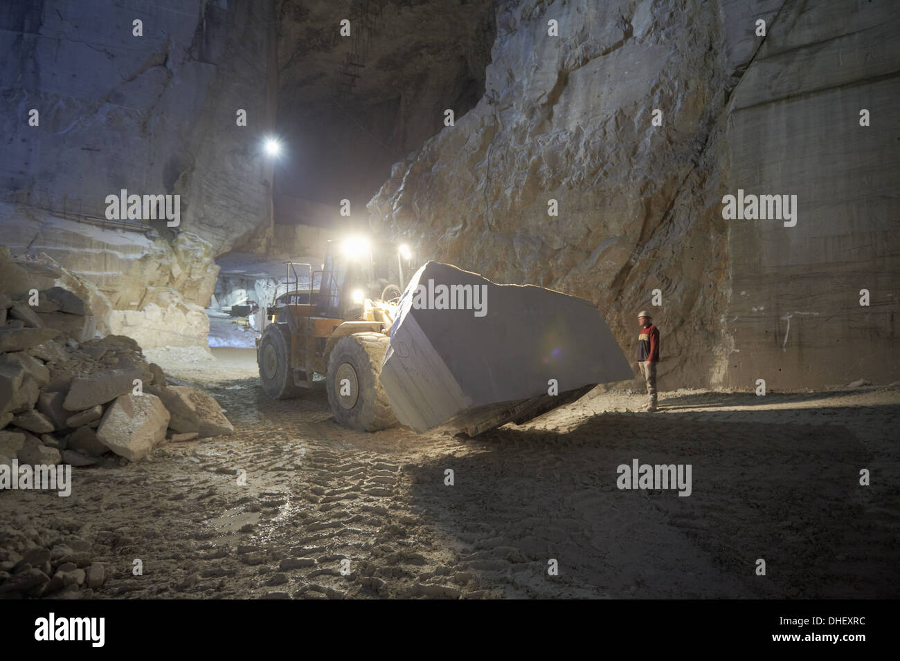 Worker and excavator in marble quarry Stock Photo
